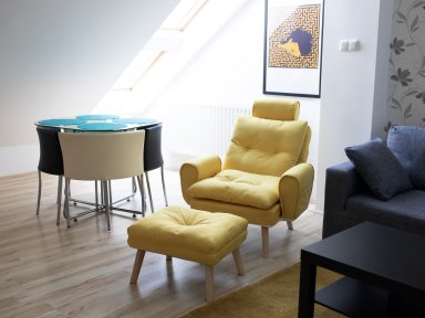 Győri órákra bérelhető lakás nappalijának részlete, fotellel és étkezősarokkal